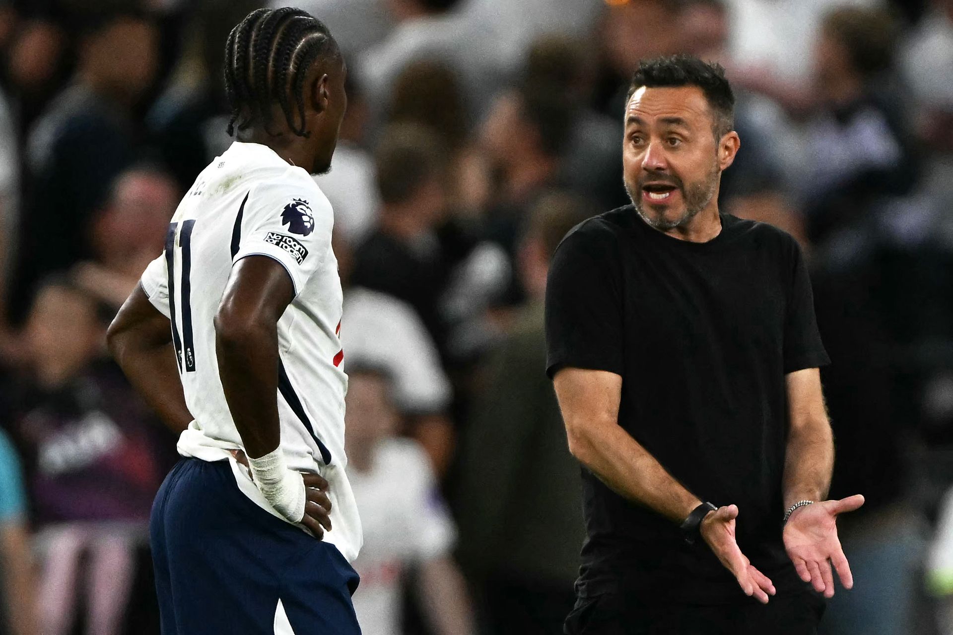 Tottenham Hotspur's French midfielder #11 Mathys Tel (L) listens to Tottenham Hotspur's Italian head coach Roberto De Zerbi